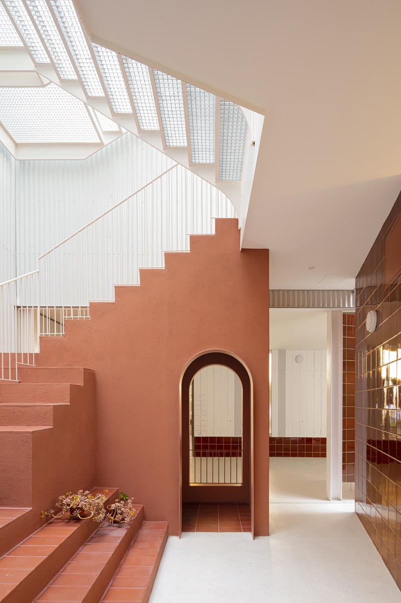 Churruca-BeStudio: hall de entrada planta baja con escalera metálica y cerámica de tonos terracota