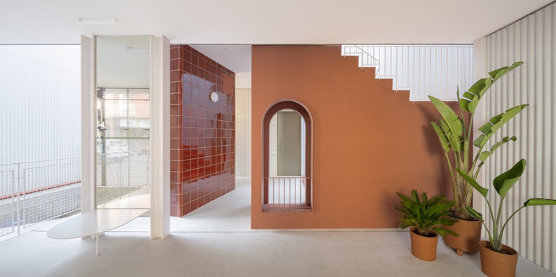 Churruca-BeStudio: detalle hall de entrada planta baja con escalera metálica y cerámica de tonos terracota