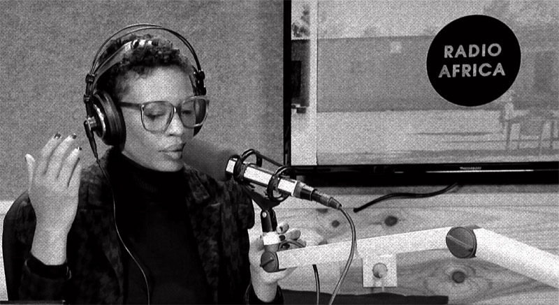Manifesta. Imagen de mujer negra ante un micrófono.