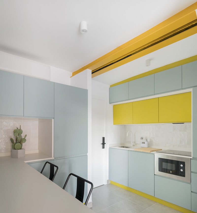 OOIIO-Arquitectura-Apartamentos-Man: cocina celeste con vigas amarillas
