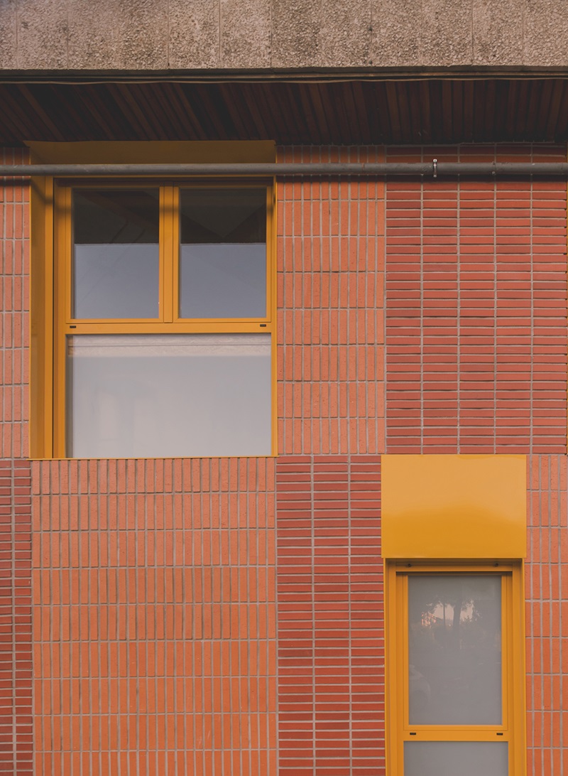 OOIIO-Arquitectura-Apartamentos-Man: fachada de ladrillo con marcos amarillos