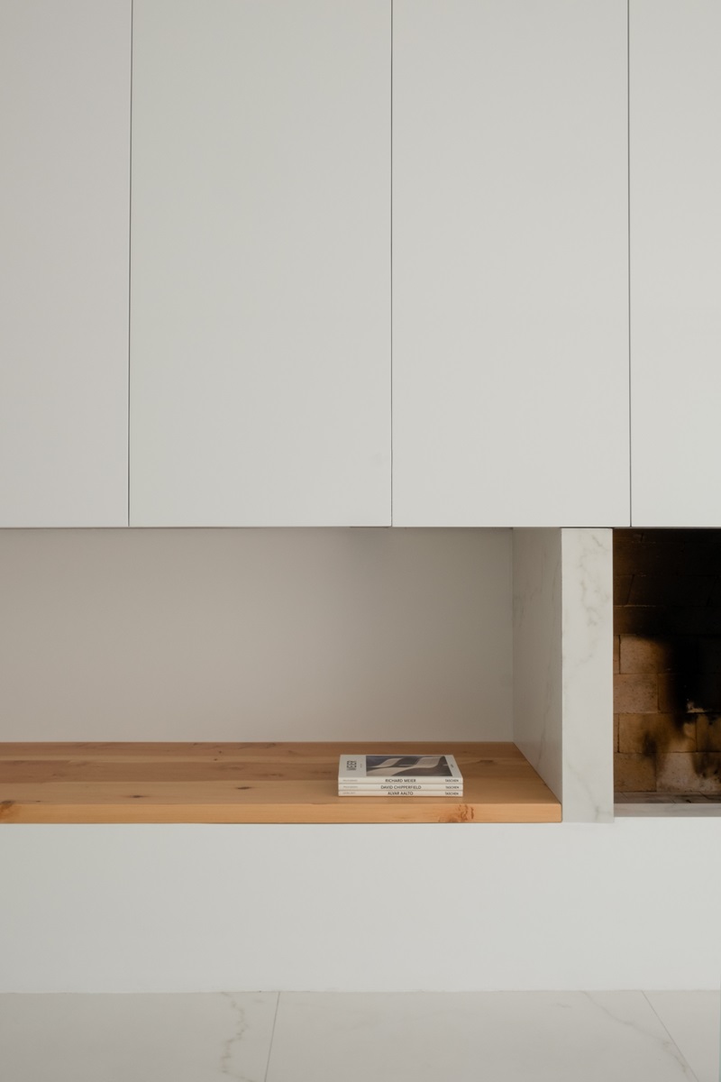 Wow-Estudio-Blanco-Calido: detalle de la estantería y la chimenea en amplio salón blanco