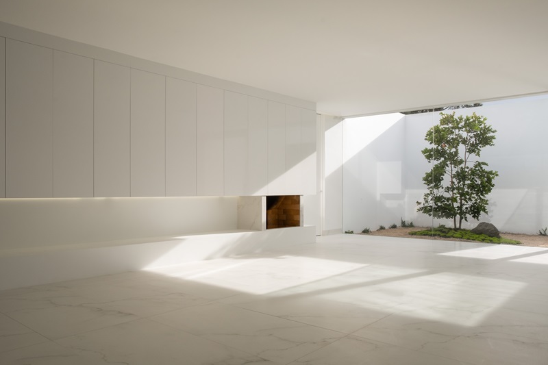 Wow-Estudio-Blanco-Calido: salón minimalista con chimenea abierto al patio
