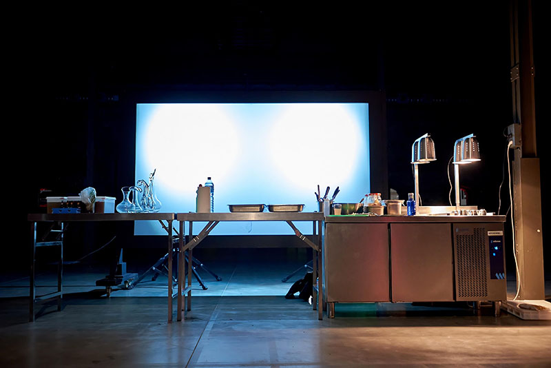 Fondo Supper Club: una cocina que parece un laboratorio, con una gran pantalla detrás