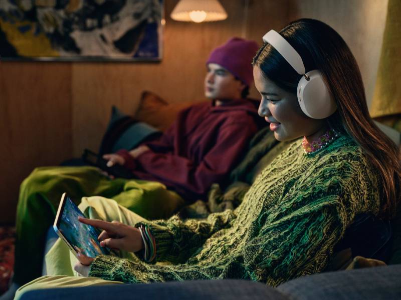Sonos Ace: una mujer con los auriculares blancos mientras maneja una tablet.