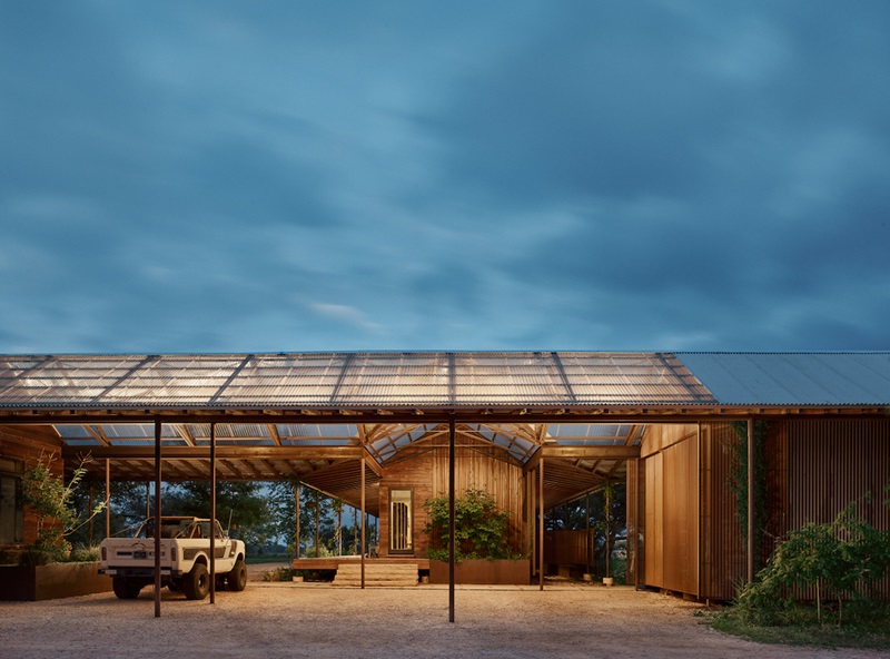 Baldridge-Architects-Roam-Ranch: rancho con cubierta inclinada de paneles de policarbonato translúcido en la naturaleza por la noche