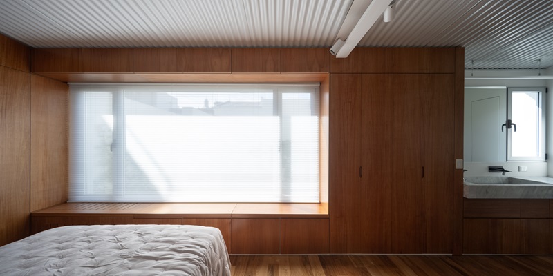 Estudio-Damero-Casa-Planes: dormitorio principal enmarcado en madera con gran ventanal