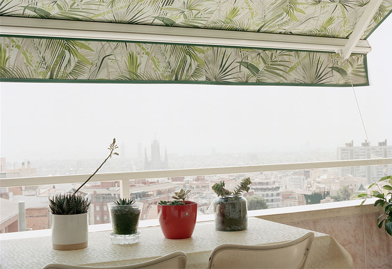 Una ciudad desconocida bajo la niebla. en la fotografía se ve una terraza con plantas y toldo