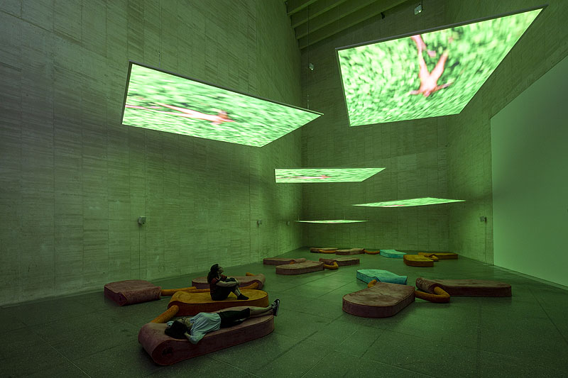 musac - imagen de una gran sala de museo con paredes de hormigón , con pantallas colgadas del techo