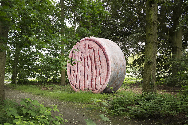 Imagen de una escultura redonda de piedra en medio de un jardín