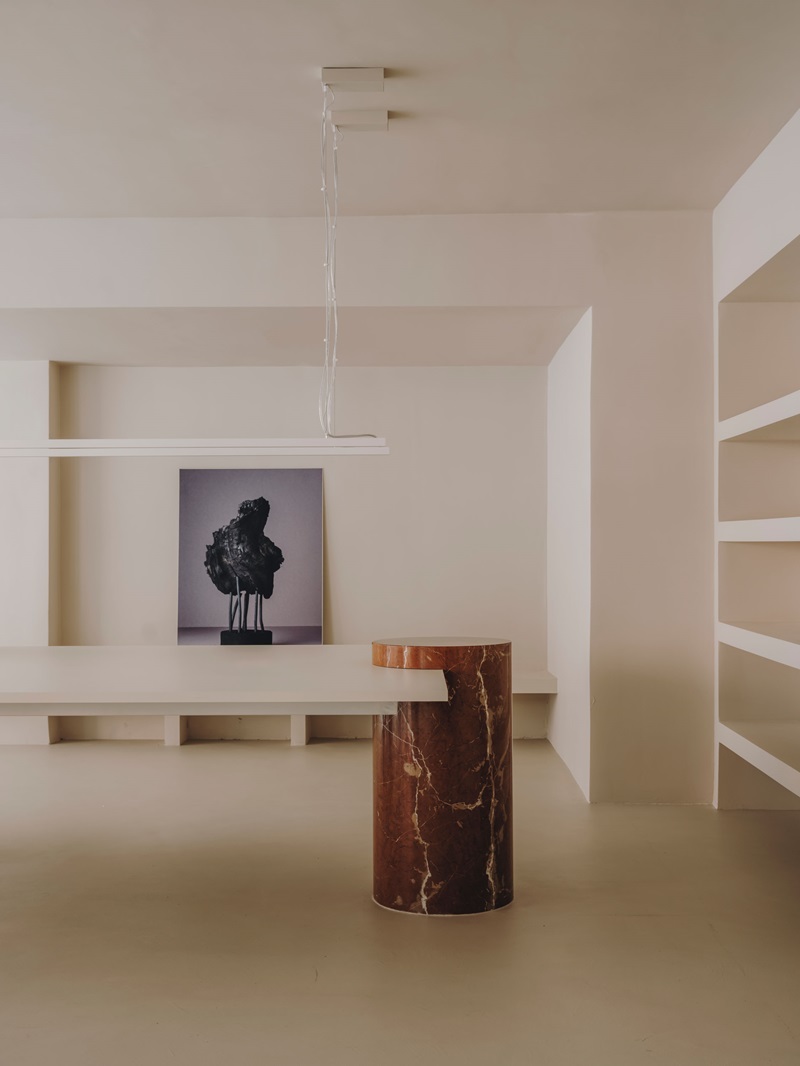 Isern-Serra-Plate-Selector: mesas de trabajo de estilo minimalista con pata cilindro de mármol rojo de Alicante y estantería de pared