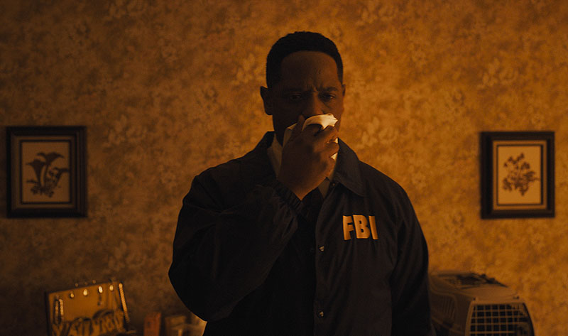 Longlegs - fotograma de la película, se ve a un agente del FBI tapándose la boca con un pañuelo