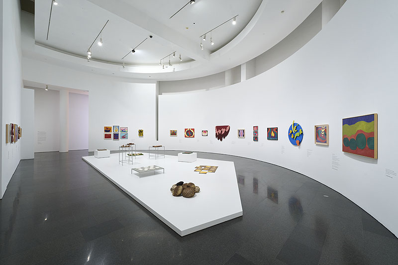 Mari Chorda, vista de una sala de exposición con pinturas y esculturas de mucho color