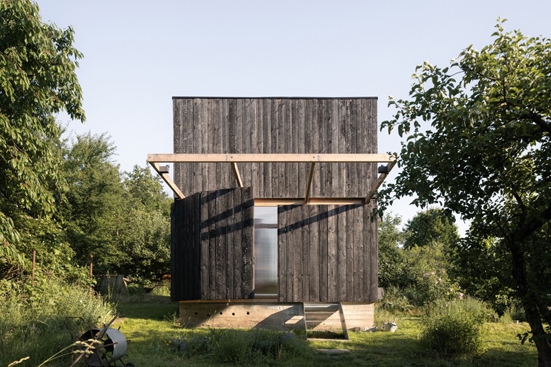 byro-architekti-garden-pavilion: pabellón de madera oscura con fachada plegable en mitad de la naturaleza