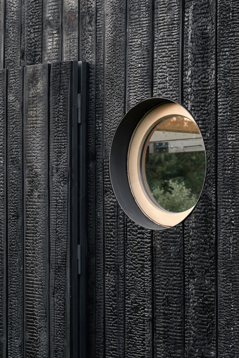 byro-architekti-garden-pavilion: pabellón con ojo de buey en fachada de madera oscura