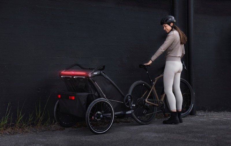 cochecitos urbanos: una mujer se prepara para salir con la bici y su Thule Chariot 2
