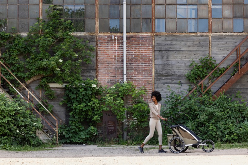 cochecitos urbanos: una mujer pasea por un núcleo urbano con su Thule Chariot 2