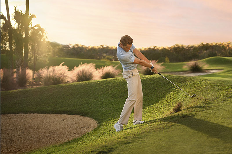 Garmin relojes inteligentes: Un hombre jugando al golf en un campo al amanecer