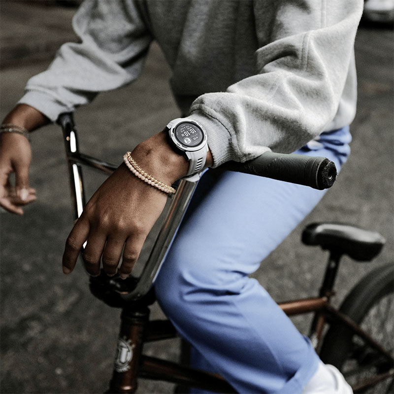 Garmin relojes inteligentes: Un plano medio de los bazos y piernas de un hombre en una bicicleta que porta un reloj inteligente de Garmin