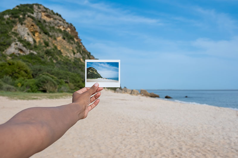 Instax Wide 400 Fujifilm: un brazo sujeta una copia enfrente de una playa
