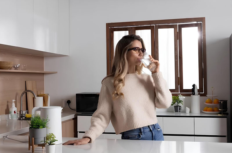 mejores gafas inteligentes: una mujer bebe un baso de agua con las gafas puestas en una cocina