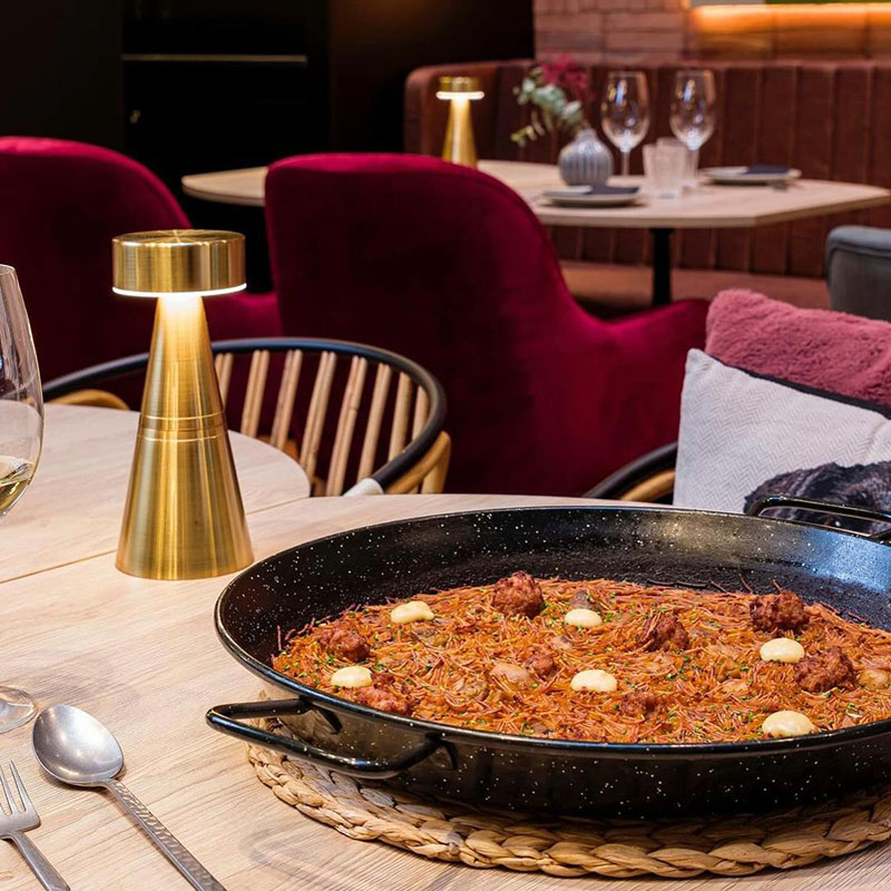 Restaurante Reversible Barcelona: una mesa con paella y una pequeña lámpara dorada