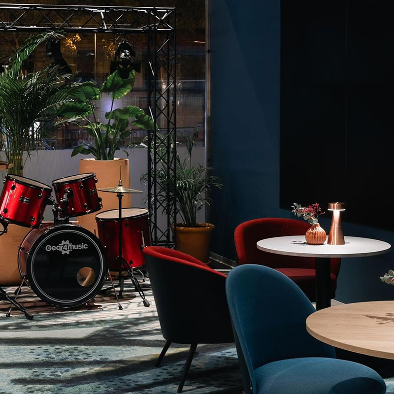 Restaurante Reversible Barcelona: mesas con butacas de colores y al fondo una batería preparada para una actuación