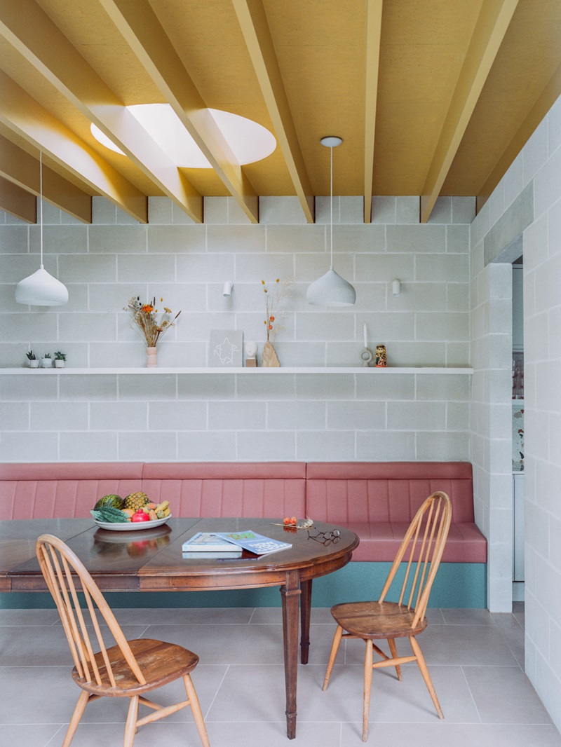 Triangle-House-Artefact: comedor con sofá rosa y techo dorado