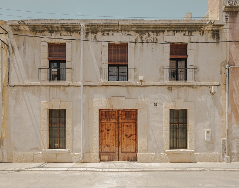 VVAA-studio- Migdia-II: fachada en tono crudo de arquitectura tradicional con portón de madera