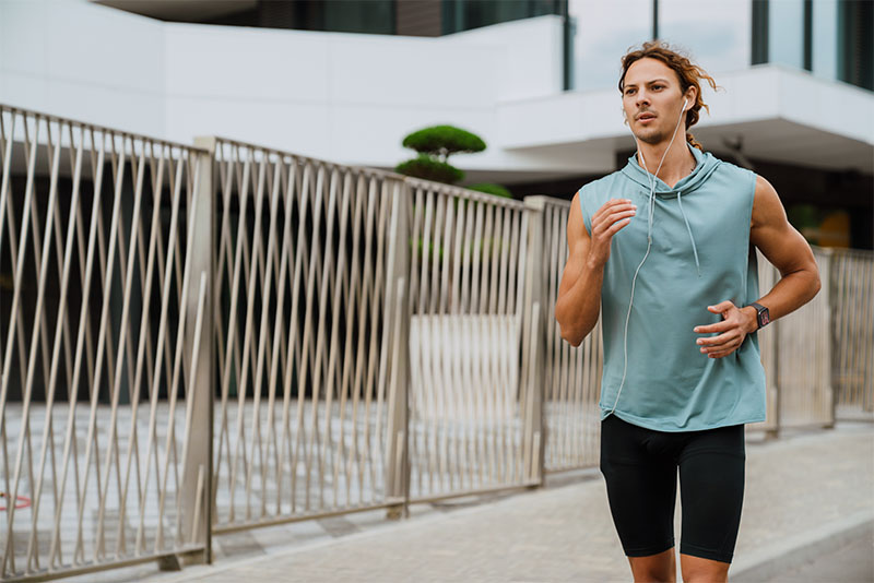 Amazfit Active: un hombre va corriendo con ropa de deporte, cascos con cable y el reloj inteligente Amazfit Active