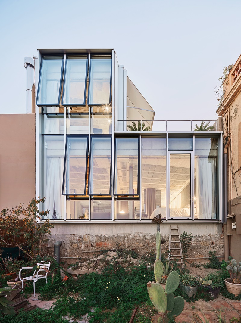 Claudia-Raurell-Villain-House: una fachada de cristal con vistas al jardín posterior