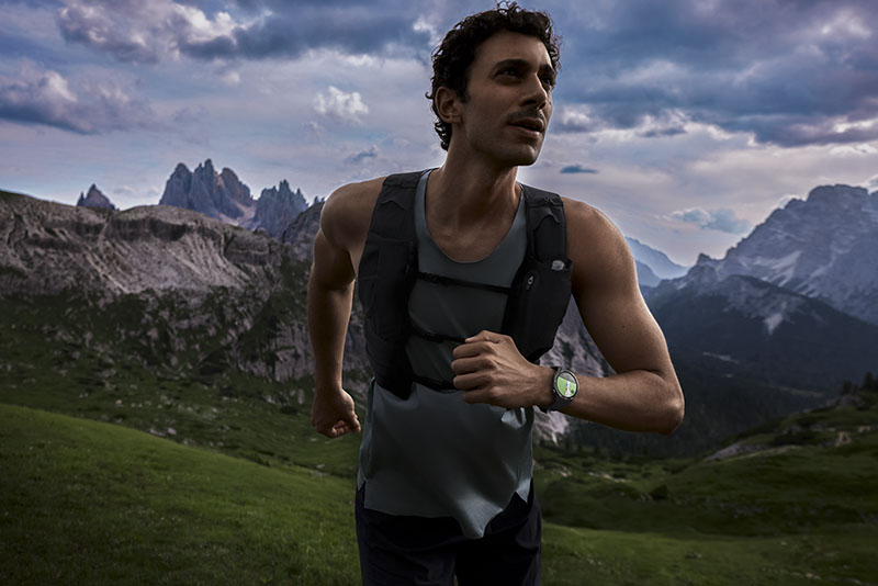 Huawei Watch GT 5 Pro: un hombre joven y musculoso va corriendo en un paisaje montañoso monitorizando su actividad física con el reloj inteligente Huawei Watch GT 5 Pro de Titanio