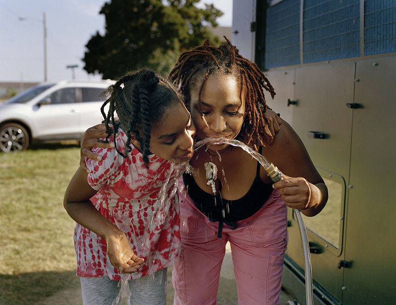 Imagen de dos mujeres bebiendo agua de manguera