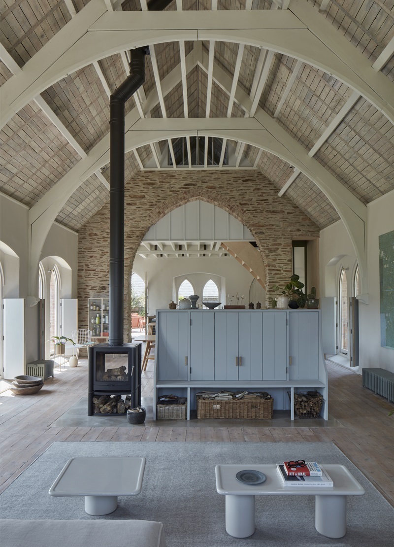 Tuckey-Design-Studio-The-Old-Chapel: salón con estufa de leña y mueble azul pastel