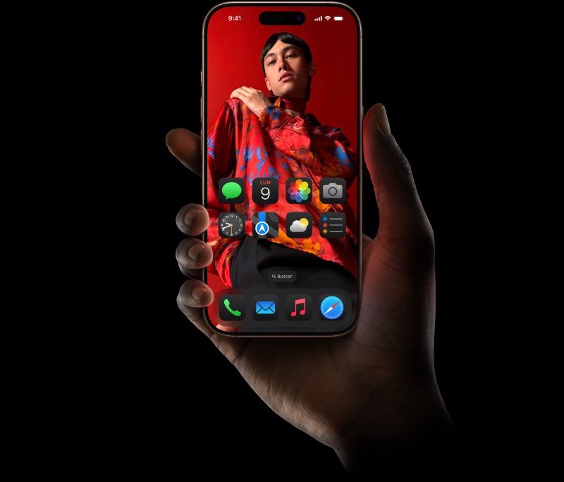 iPhone 16: una mano sostiene el dispositivo con pantalla de alta definición y personalizada sobre fondo negro de estudio