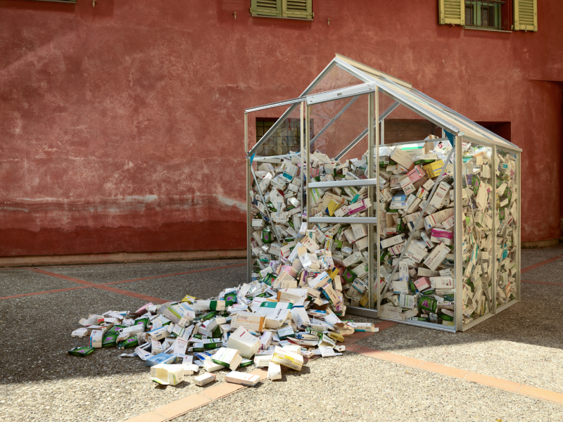 Imagen de casa de cristal con cojas de medicamentos