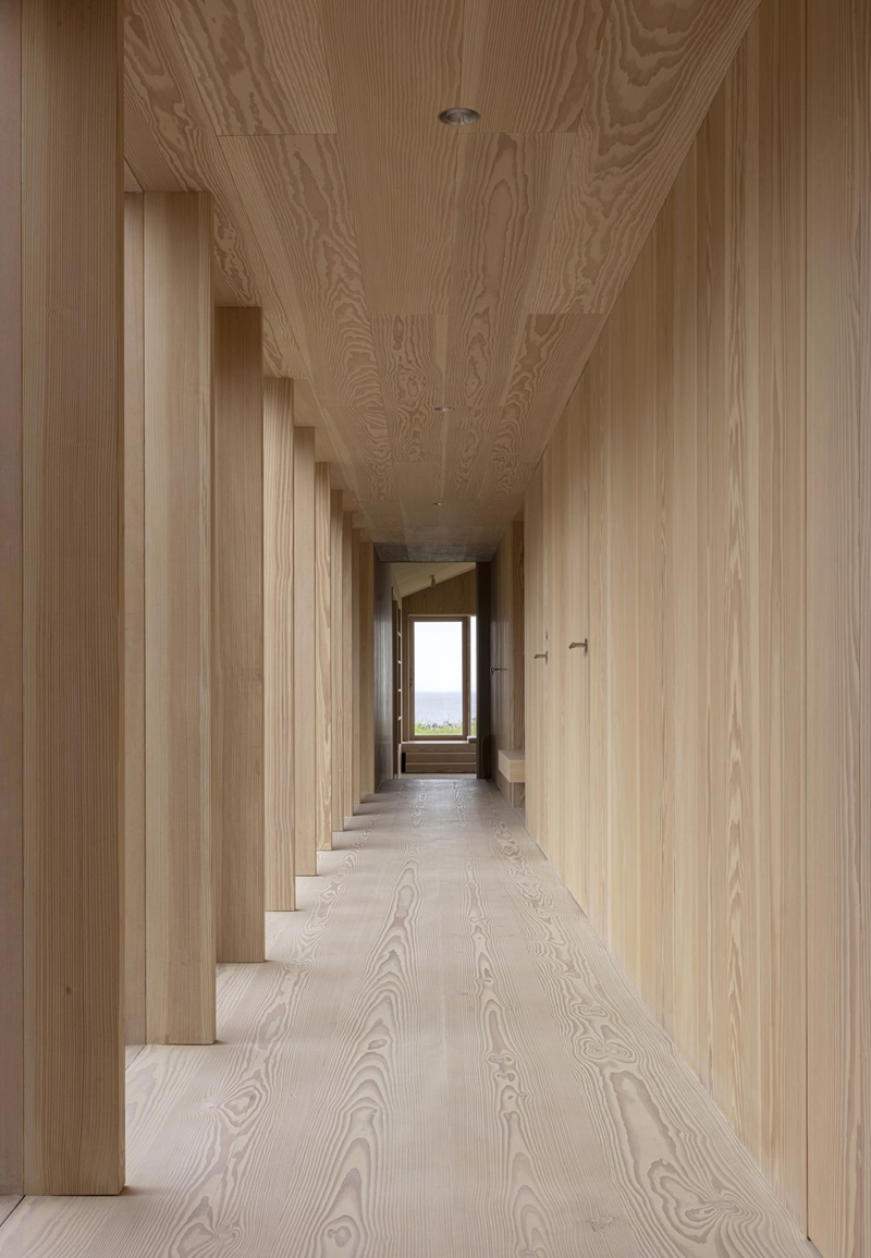 Norm-Architects-Heatherhill-Beach-House: corredor exterior con pilares de madera