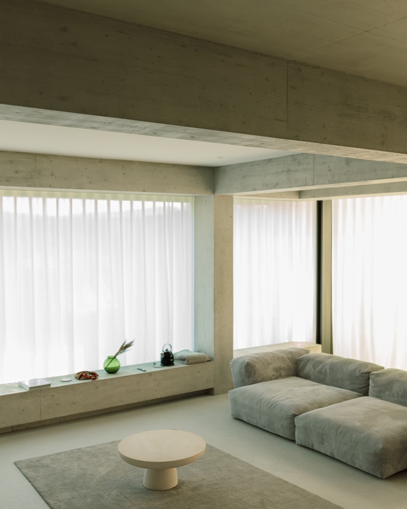 Oberwil-House-Caesar-Zumthor: sala de estar con vigas y pilares de hormigón con sofá gris