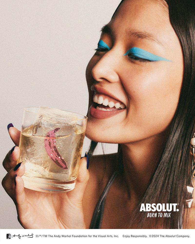 Absolut Warhol: cartel publicitario del rostro de una modelo maquillada con sobra de ojos azul turquesa, que sujeta un cócktail de vodka próximo a su boca.