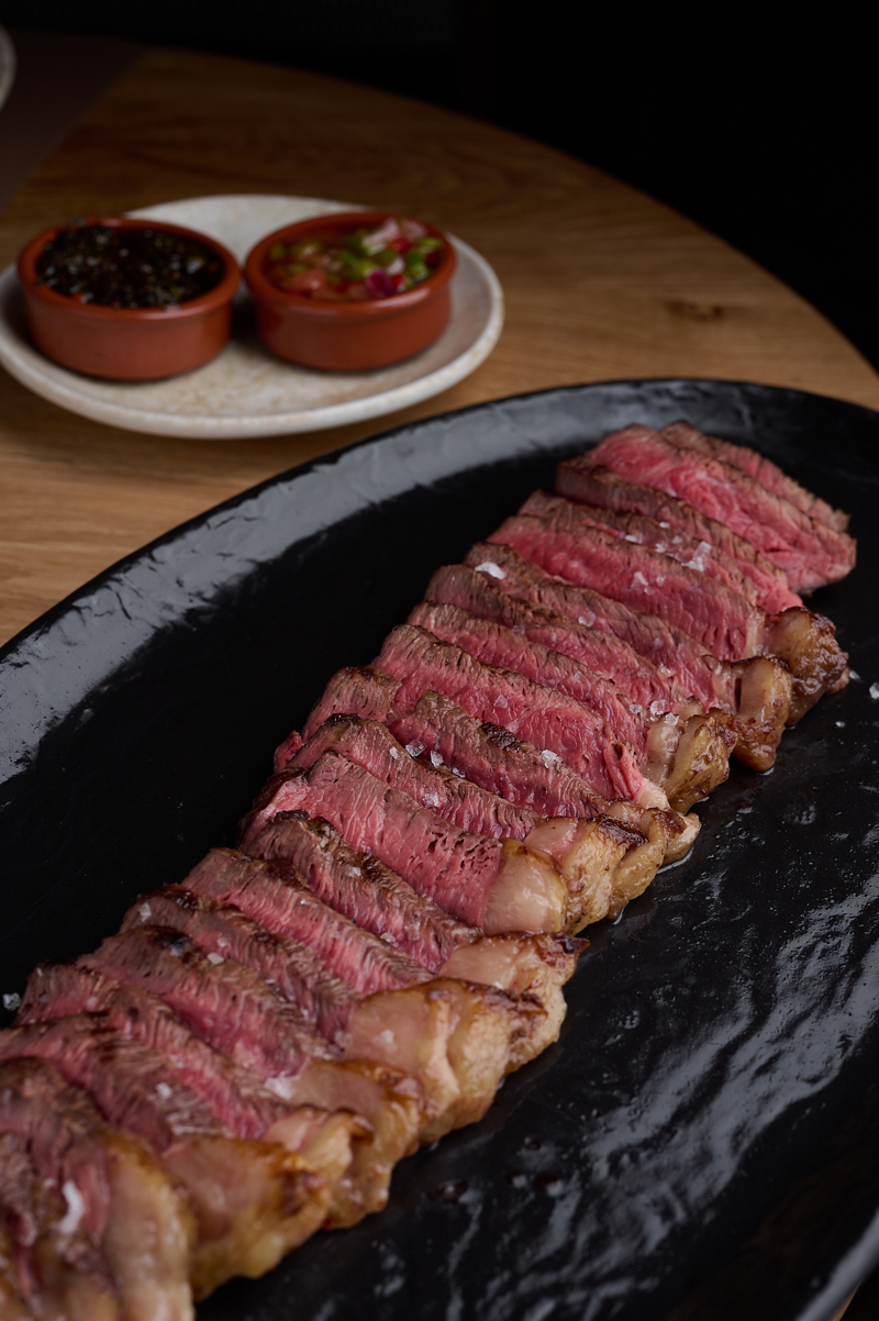 Al Fuego Madrid: carne cocinada, fileteada y dispuesta en una bandeja negra