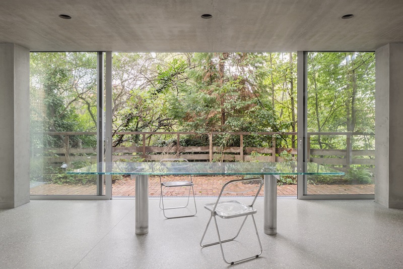 Gianni-Botsford-Architects-Reciprocal-House: salón con mesa de cristal y ventanal abierto al jardín