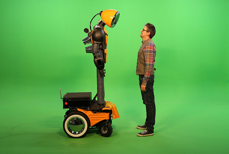 Hombre frente a robot con un fondo verde