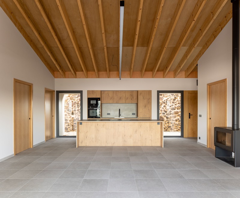 Onyon-Arquitectura-Korta: cocina con isla y techo inclinado de viguetas de madera laminada