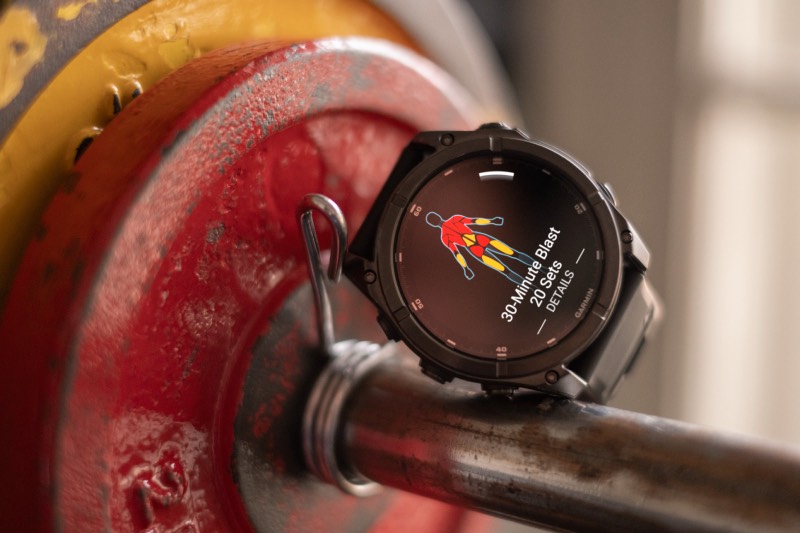 Garmin: un reloj Fenix 8 de Garmin descansa sobre unas pesas mientras muestra la serie de ejercicios y repeticiones en la pantalla.