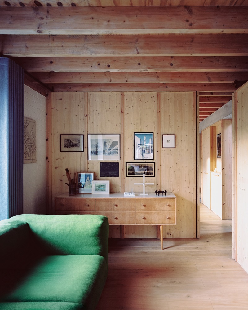 31-44-Six-Columns: sala de estar de madera con sofá verde y fotos