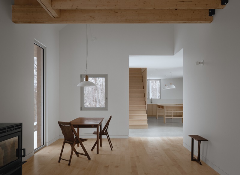 Julia-Manaças-Architecte-House-MN: sala de estar con suelo de madera y mesa de comedor y estufa de leña