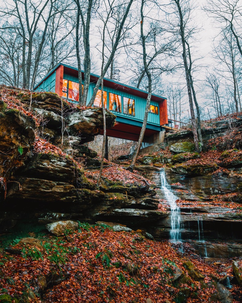 Airbnb: un contenedor convertido en alojamiento de alquiler sobre un barranco natural por el que cae el agua formando una pequeña cascada.