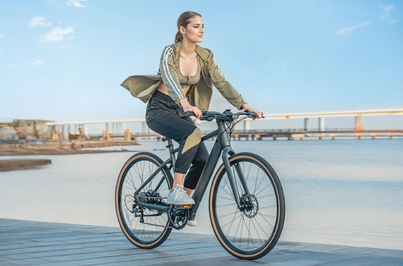 bicicleta eléctrica urbana: una mujer va de paseo en un día soleado con la bicicleta eléctrica urbana C21 de Fiido