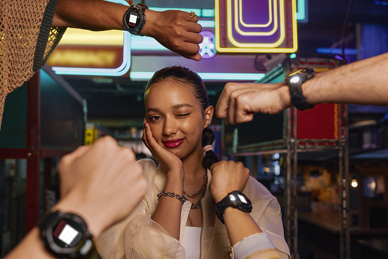 Garmin Instinct smartwatch: una chica posa junto a un montón de brazos con este modelo y la linterna activada