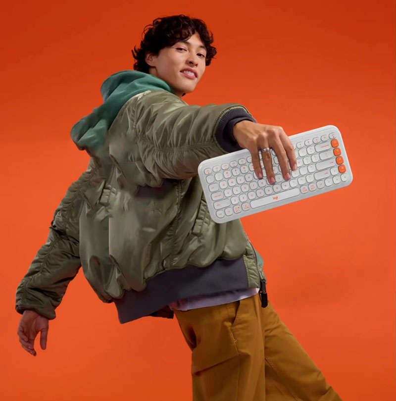 Teclado Logitech Pop Icon Keys: un chico sujentando un teclado de color blanco con algunas teclas naranjas